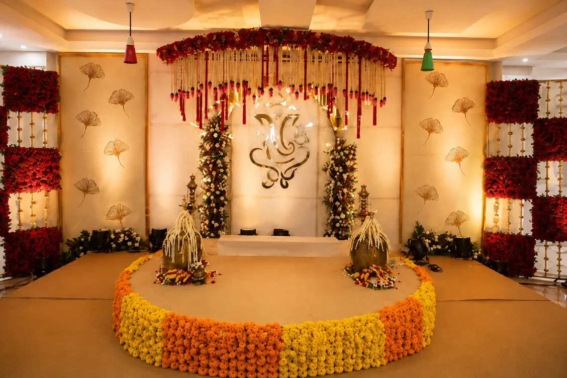 Mandap with a decorated backdrop, hanging florals and a marigold-edged stage