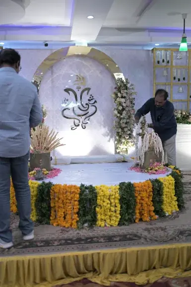 Wedding stage being decorated with a peacock motif backdrop and marigold garlands