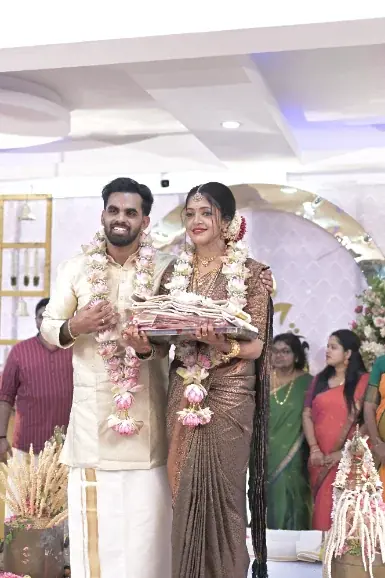 Bride and groom in traditional Kerala wedding attire holding garlands on the stage