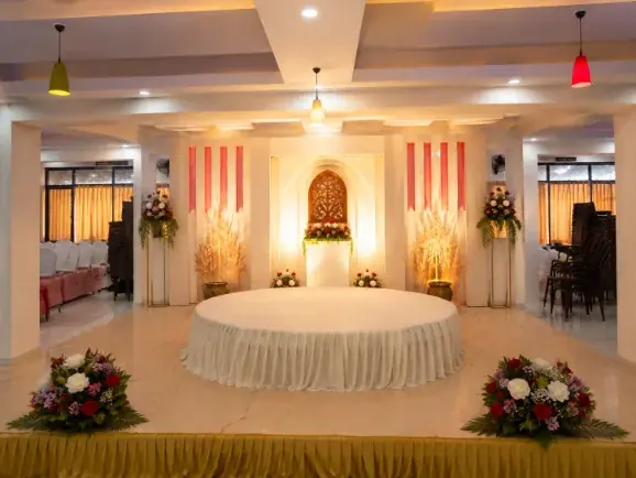 Round ceremony stage with cream and gold drapes and floral pillars